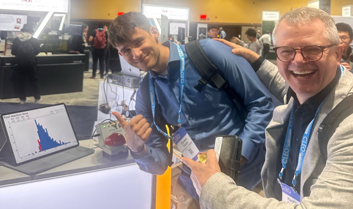 Professor Herald Giessen and student Florent Kadriu posing next to the Button Presser Game, shortly after playing