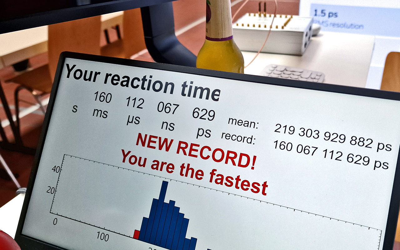 Swabian Instruments booth during DPG 2025 showing reaction time measurement results, including values in seconds, milliseconds, microseconds, nanoseconds, and picoseconds, a new record notification, and a histogram of event distribution.