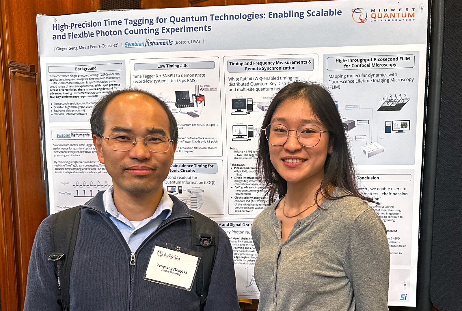 Professor Tongcan Li (Purdue University, left) and Ginger Geng (Swabian Instruments, right) stand smiling in front of a Swabian Instruments poster titled High Precision Time Tagging for Quantum Technologies: Enabling Scalable and Flexible Photon Counting Experiments. The poster highlights Time Tagger applications in timing and frequency measurements, and high-throughput picosecond FLIM for confocal microscopy, with details visible in the background.