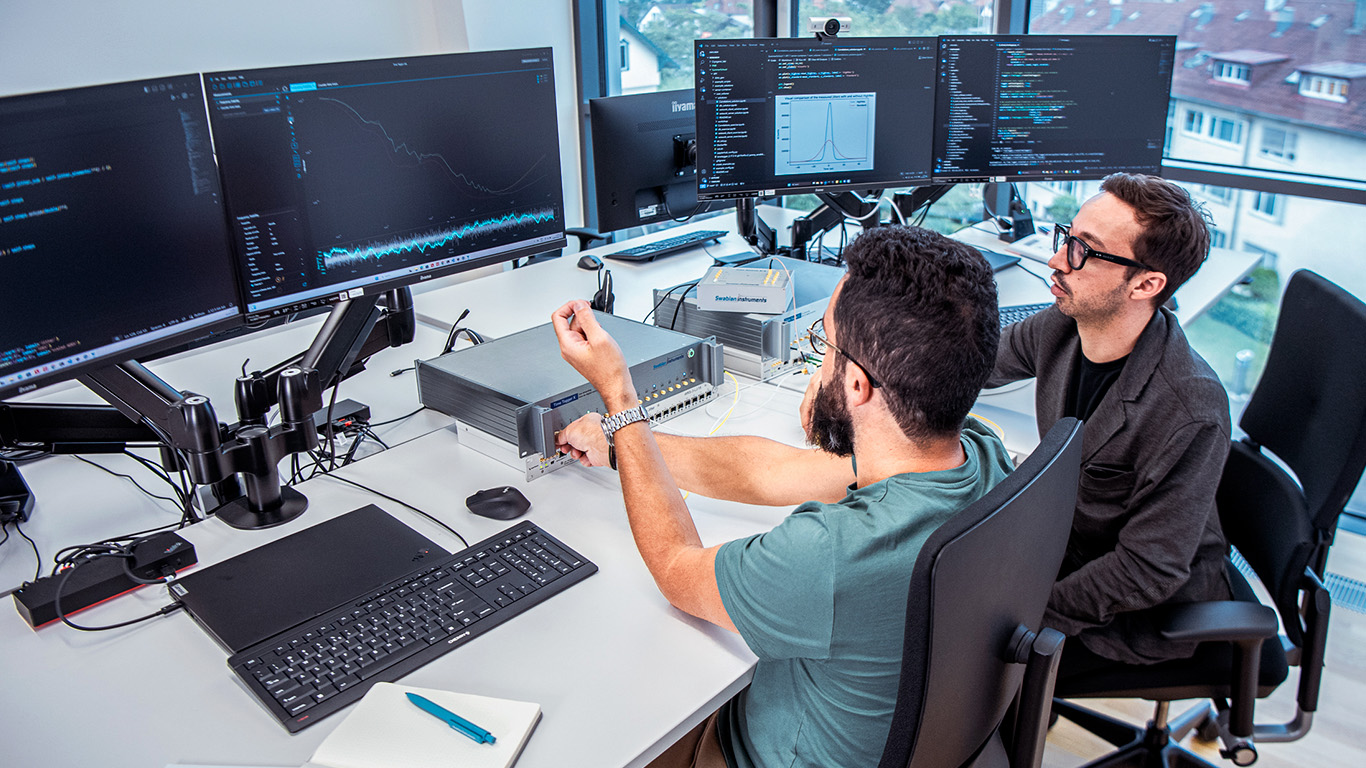 Two support team members evaluating the performance of the Time Tagger Lab using a Time Tagger X.
